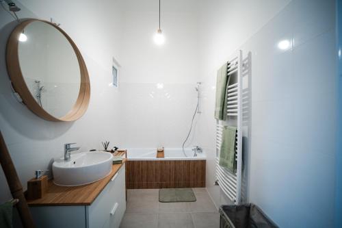 een badkamer met een wastafel, een spiegel en een bad bij Volenter Lux Apartment Uno in Baja
