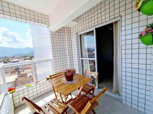 een tafel en stoelen op een balkon met een raam bij Lindo apto com piscina em Praia Grande - QX01H in Solemar