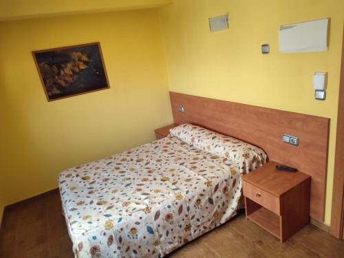 um pequeno quarto com uma cama e uma mesa de madeira em Pension Urola em Zumárraga