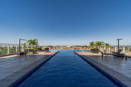 uma piscina num resort com palmeiras em Condomínio Residencial Duo JK Sky - São José do Rio Preto em Sao Jose do Rio Preto