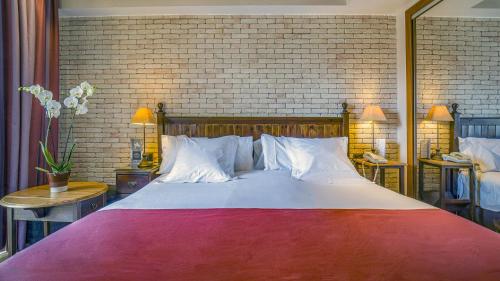 een groot bed in een slaapkamer met een bakstenen muur bij Roc Blanc Hotel & Spa in Andorra la Vella