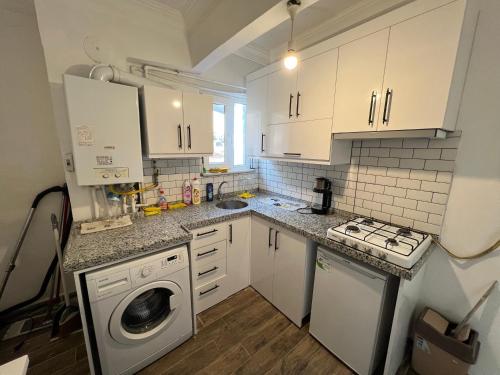 a kitchen with white cabinets and a washing machine at NOBIS Cihangir Apartments in Istanbul