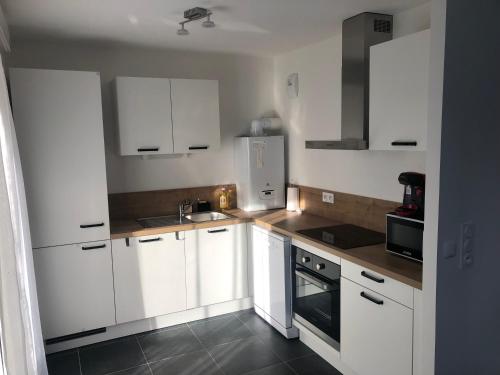 une cuisine avec des armoires blanches et un four à plaques de cuisson dans l'établissement Echappée mer - 4 pers - Parking privé - Ascenseur - 60m2, au Havre