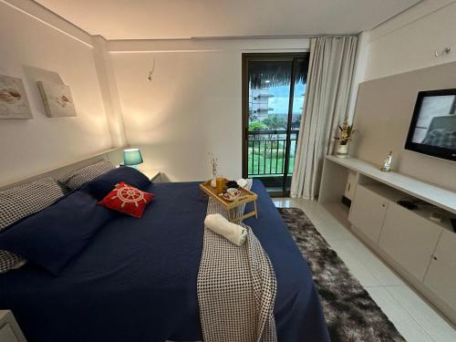 ein Schlafzimmer mit einem blauen Bett und einem TV in der Unterkunft RIVIERA MANHATTAN - Luxuoso 4 quartos, varanda Gourmet in Aquiraz