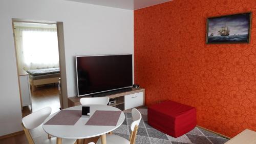 ein Wohnzimmer mit einem Tisch und einer roten Wand in der Unterkunft Cozy Telliskivi apartment near city centre in Tallinn