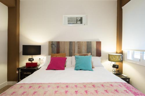 a bedroom with a large white bed with colorful pillows at MalagaSuite City Center Capuchinos in Málaga