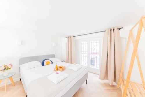a white bedroom with a bed and a window at CMG Cherche Midi - Sèvres in Paris