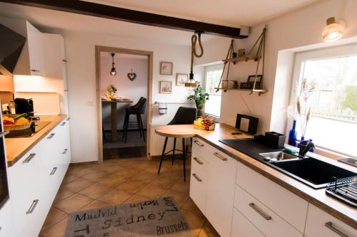 a kitchen with white cabinets and a table and a counter at Ferienwohnung Ingermann in Pommerby