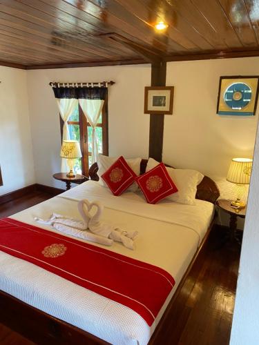 a bedroom with a large bed with red and white pillows at Soutikone Place House 2 in Luang Prabang