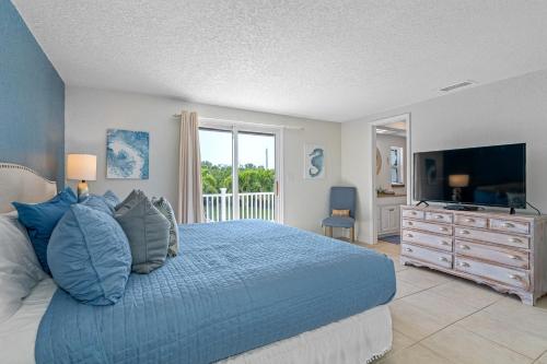 a bedroom with a blue bed and a television at Stunning Waterfront Pool Home Walk to Beach & Restaurants Large Private Pool in Clearwater Beach