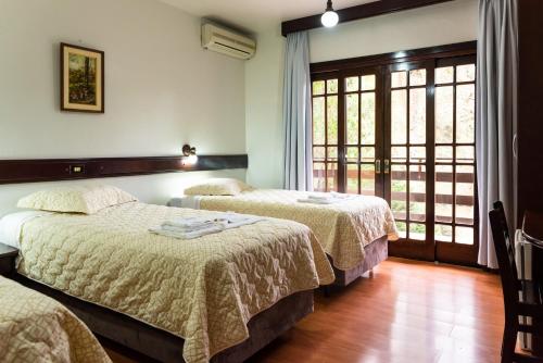 two beds in a hotel room with a window at Filadélfia Hospedagens e Eventos in São Bento do Sul