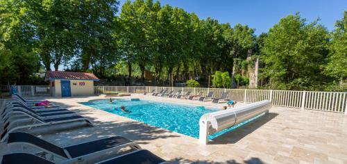 a swimming pool with chairs and people in it at Camping L'Etang D'Ardy *** in Saint-Paul-lès-Dax