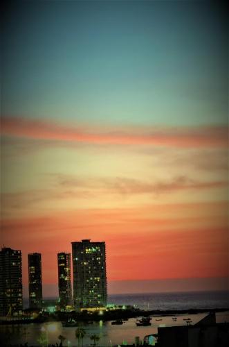 a sunset over a city with tall buildings and the ocean at Cavancha Exclusivo in Iquique