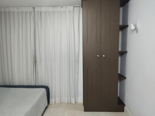 1 dormitorio con armario marrón junto a una ventana en Flat Aconchegante na Asa Sul, en Brasilia