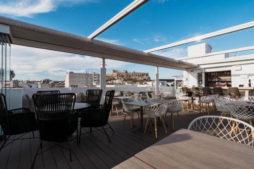 a patio with tables and chairs on a balcony at Acropolis Select in Athens