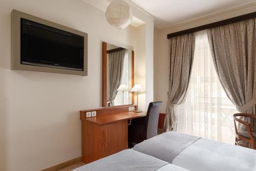 a hotel room with a bed and a desk and a television at Acropolis Select in Athens