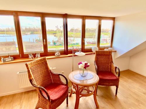 two chairs and a table in a room with windows at Bummert Am Hafen 2 Greetsiel in Krummhörn