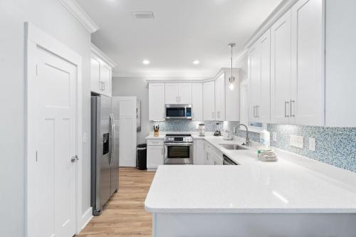 una gran cocina blanca con armarios y electrodomésticos blancos en Barefoot Bungalow at Rookery, en Gulf Shores