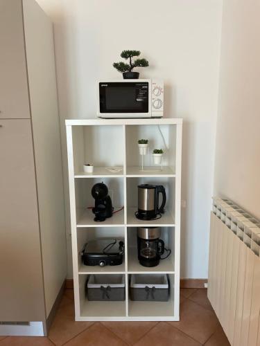 ein weißes Bücherregal mit einer Mikrowelle und Geräten in der Unterkunft Apartments Terranova in Rovinj