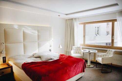 a bedroom with a bed and a table and a window at Hotel Arte in St. Moritz