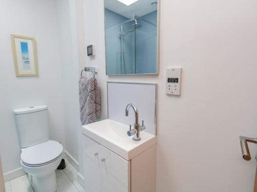 La salle de bains est pourvue de toilettes, d'un lavabo et d'un miroir. dans l'établissement Beach Retreat, à Weymouth