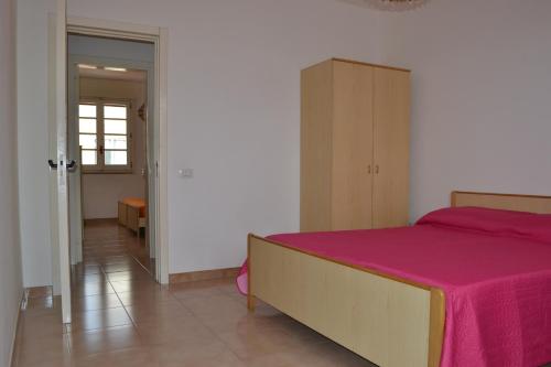 um quarto com uma cama com um cobertor rosa em Apt 7 Posti Vicino Spiaggia em San Foca