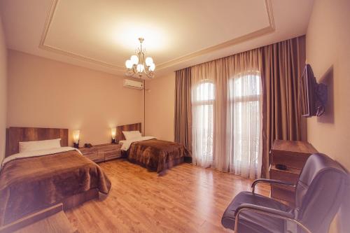 una habitación de hotel con 2 camas y una silla en Royal Venezia Hotel, en Batumi