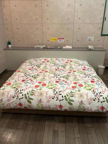 a bed with a floral comforter in a room at ホテルSpace24 in Miyakonozyō