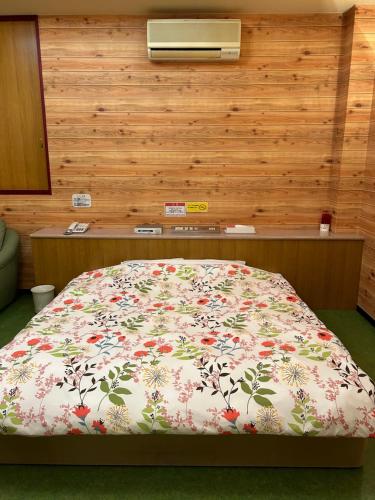 a bedroom with a bed with a floral comforter at ホテルSpace24 in Miyakonozyō