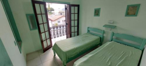 a room with two beds and a window with a view at Sobrado com piscina em condomíno fechado a 150 M da praia in Caraguatatuba