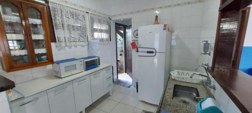 a kitchen with a white refrigerator and a sink at Sobrado com piscina em condomíno fechado a 150 M da praia in Caraguatatuba