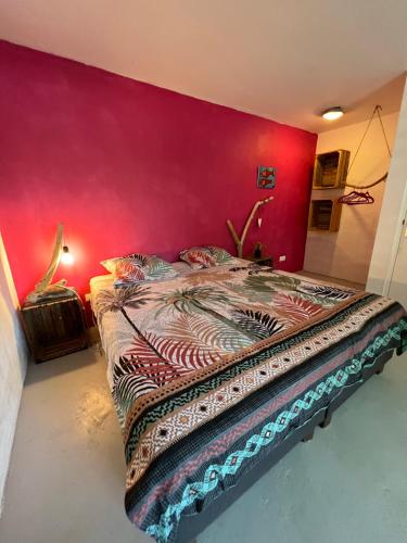 een slaapkamer met een groot bed met een rode muur bij Tropical Breeze Curaçao 'Blenchi' in Willemstad