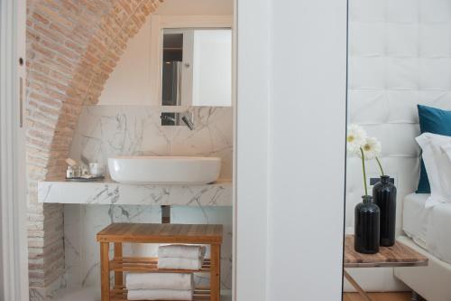a bathroom with a white sink and a brick wall at Argentina Residenza Style Hotel in Rome