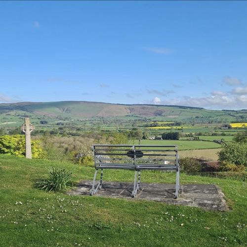 a bench sitting on top of a grassy hill at The Harp Inn in Old Radnor