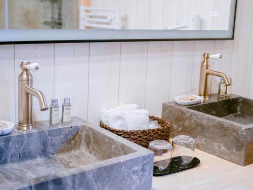 a bathroom with two sinks and a basket of towels at Cabane Château hôtel luxe avec spa privatif Aulteribe - Le Peydébé in Vieille-Brioude