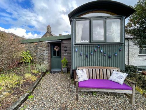 un banco sentado frente a una casa verde en 5 Star Shepherds Hut in Betws y Coed with Mountain View en Capel-Curig