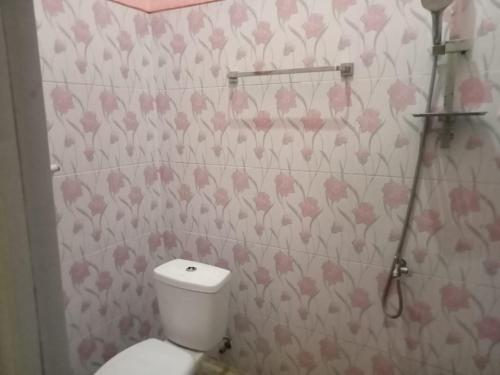 a bathroom with a toilet and pink flowers on the wall at Cahaya Homestay in Magelang