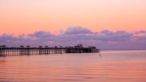 a pier on the water with a sunset at 5 Star Shepherds Hut in Betws y Coed with Mountain View in Capel-Curig