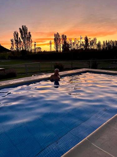 a man in a swimming pool at sunset at Cabañas Morita Mia in San Rafael