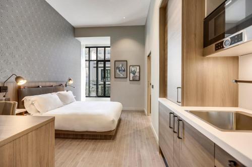 ein Hotelzimmer mit einem Bett und einem Waschbecken in der Unterkunft Mode Paris Aparthotel in Paris