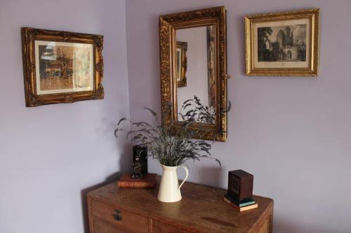 a vase on a dresser with two mirrors on a wall at Stoneleigh in Felixstowe