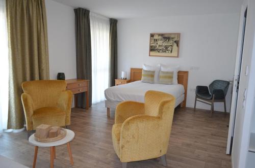 um quarto de hotel com uma cama e cadeiras e uma mesa em Résidence Les Tisserands - Domitys em Beauvais