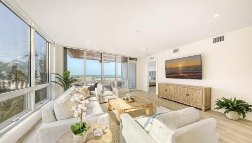 una sala de estar con muebles blancos y ventanas grandes. en Ten35 Seaside Rentals en Sarasota