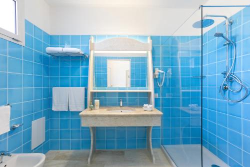 y baño azul con lavabo y ducha. en Nicolaus Club Quattro Lune Resort, en Cala Liberotto