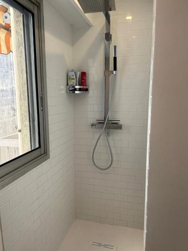 La salle de bains est pourvue d'une douche avec un tuyau et de carrelage blanc. dans l'établissement Nice la Belle, city centre 1 bed, 2 terrace, quiet, à Nice