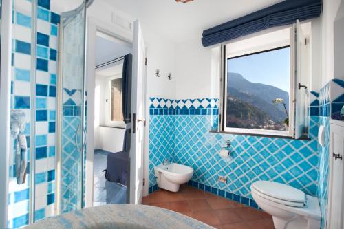 Estate4home - Villa Settemari في بوسيتانو: حمام من البلاط الأزرق مع مرحاض ونافذة