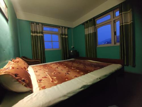 a bedroom with a bed and two windows at Hotel Gaurav in Darjeeling