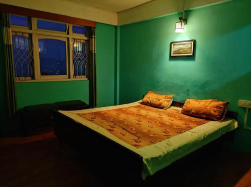 een groene slaapkamer met een bed in een kamer bij Hotel Gaurav in Darjeeling
