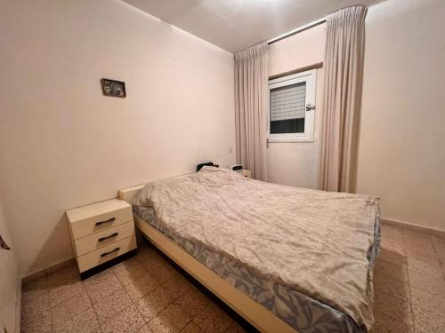 een kleine slaapkamer met een bed en een raam bij TLV Vintage 2BR in Bat Yam