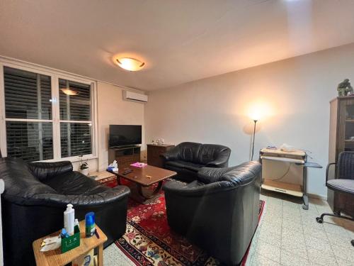 een woonkamer met lederen stoelen en een tafel bij TLV Vintage 2BR in Bat Yam